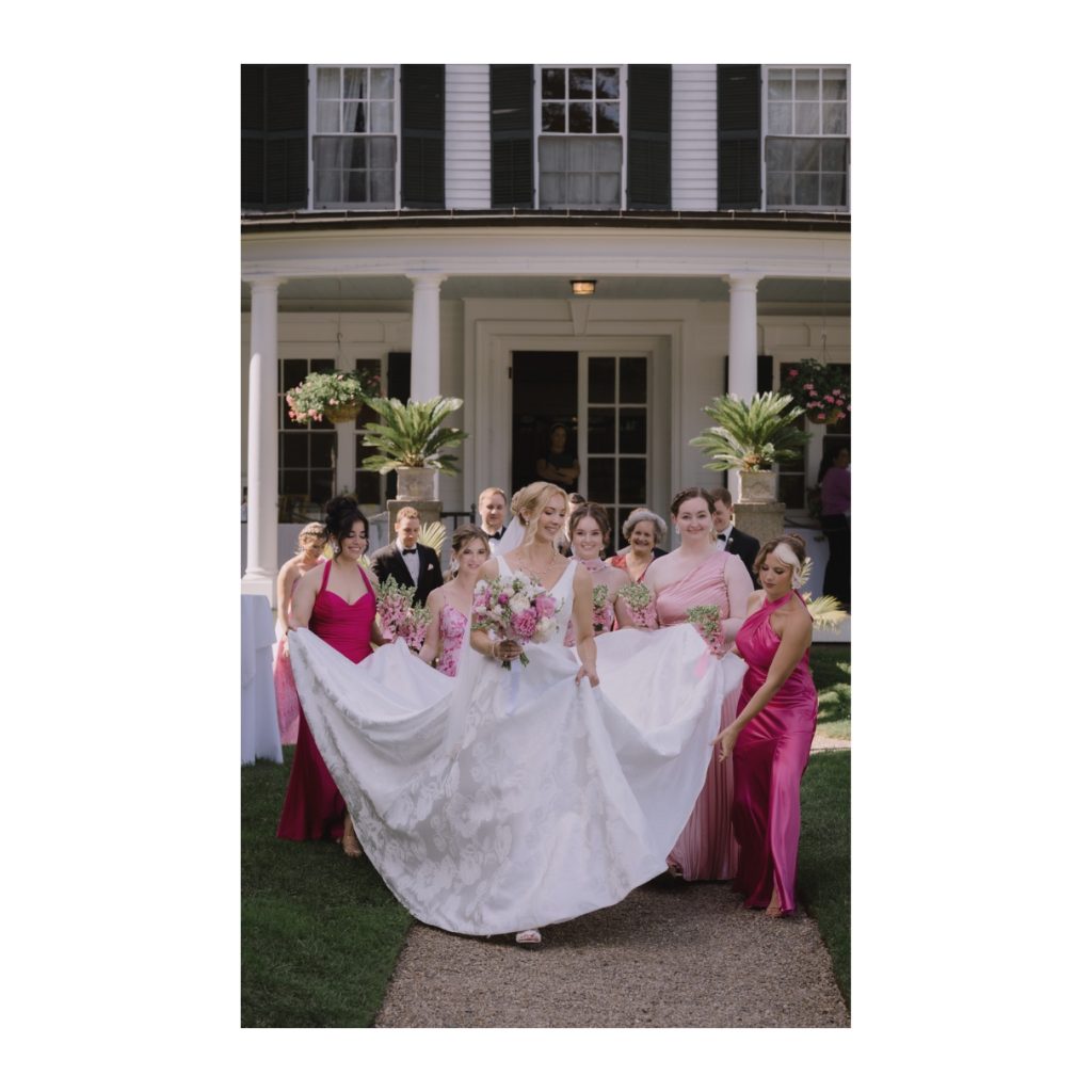 Bridal party help bride carry her dress at Glen Magna Farms. Captured by North Shore wedding photographer, Daniel Baci.
