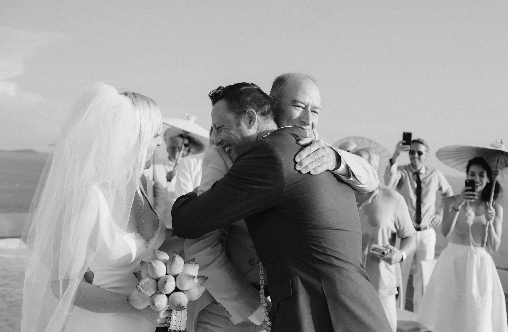 BBrides father embracing the groom with a hug as he gives the bride away at wedding ceremony on Cape Cod