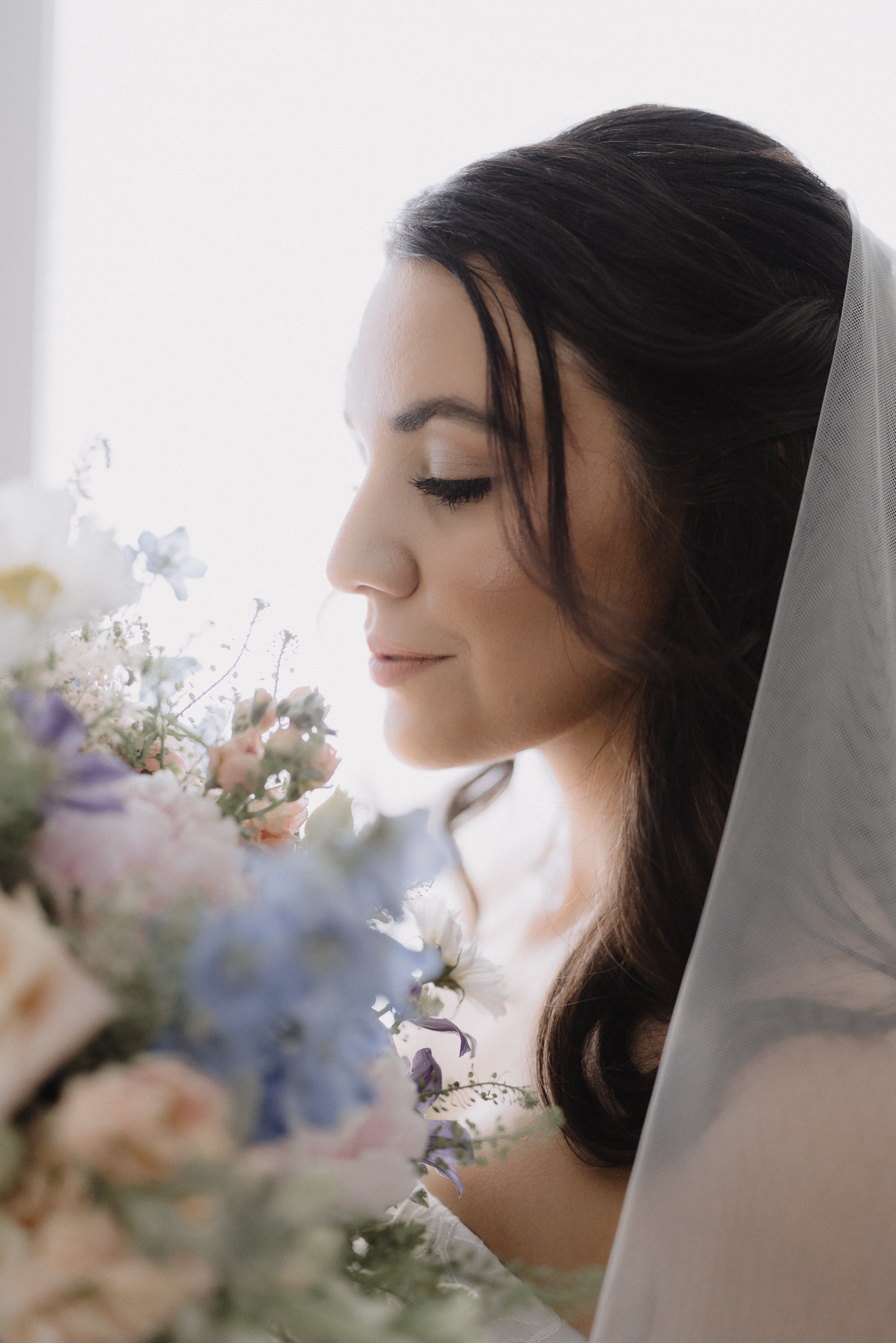 Bride poses for portrait holding her flowers closer to her face just moments before her Cape Cod wedding ceremony