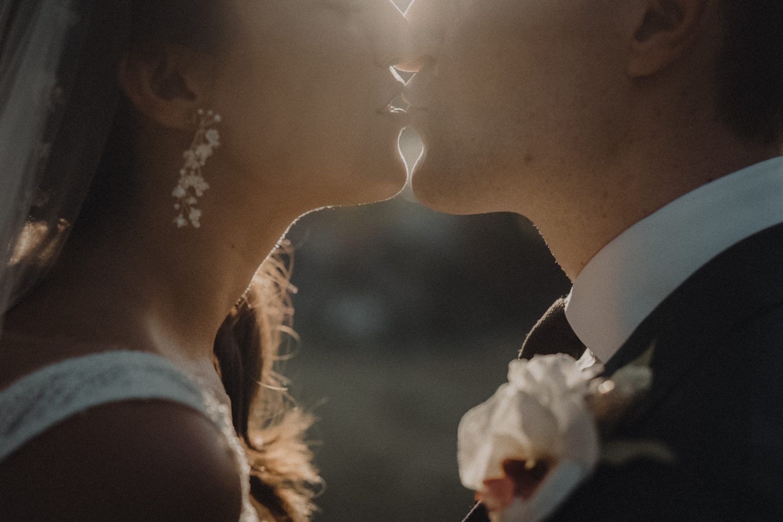 Closeup portrait of bride & groom kissing with the sun flaring through Cape Cod wedding photographers lens