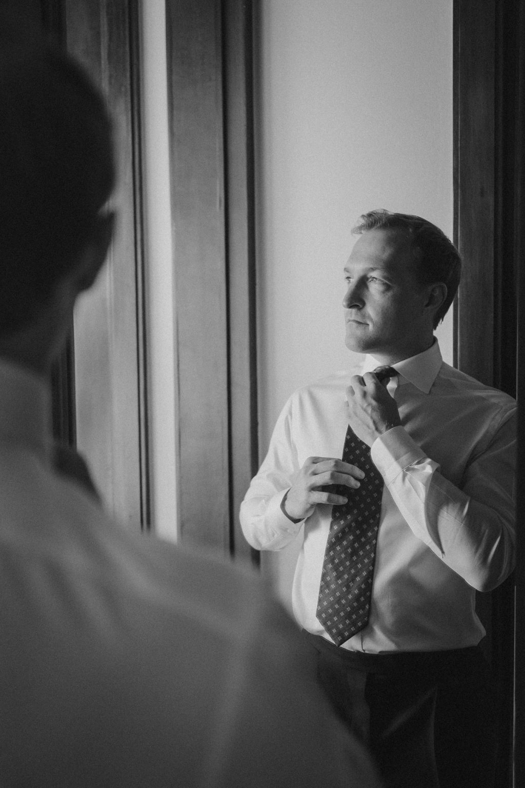 grooms portrait fixing his tie