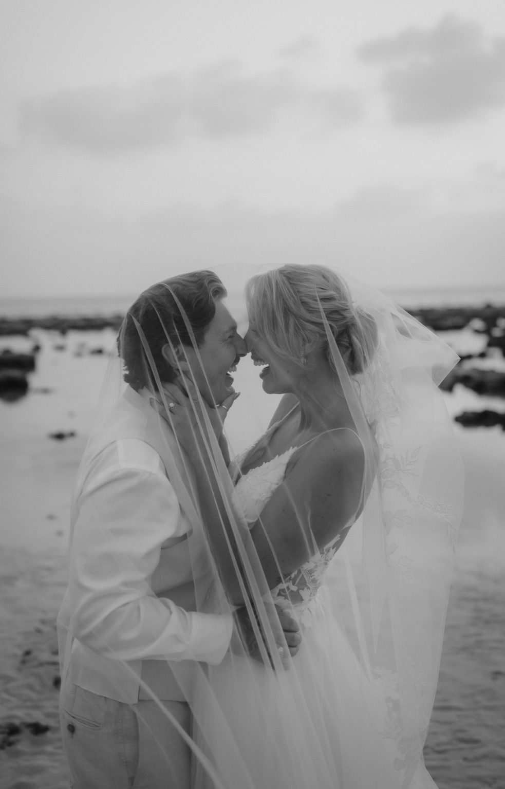 Bride and groom laughing during their elopement portrait session on the beach.