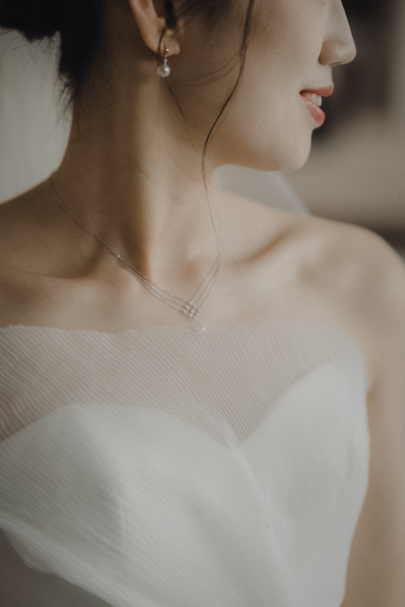 Bride in a strapless tulle wedding gown and delicate necklace, close-up wedding detail portrait