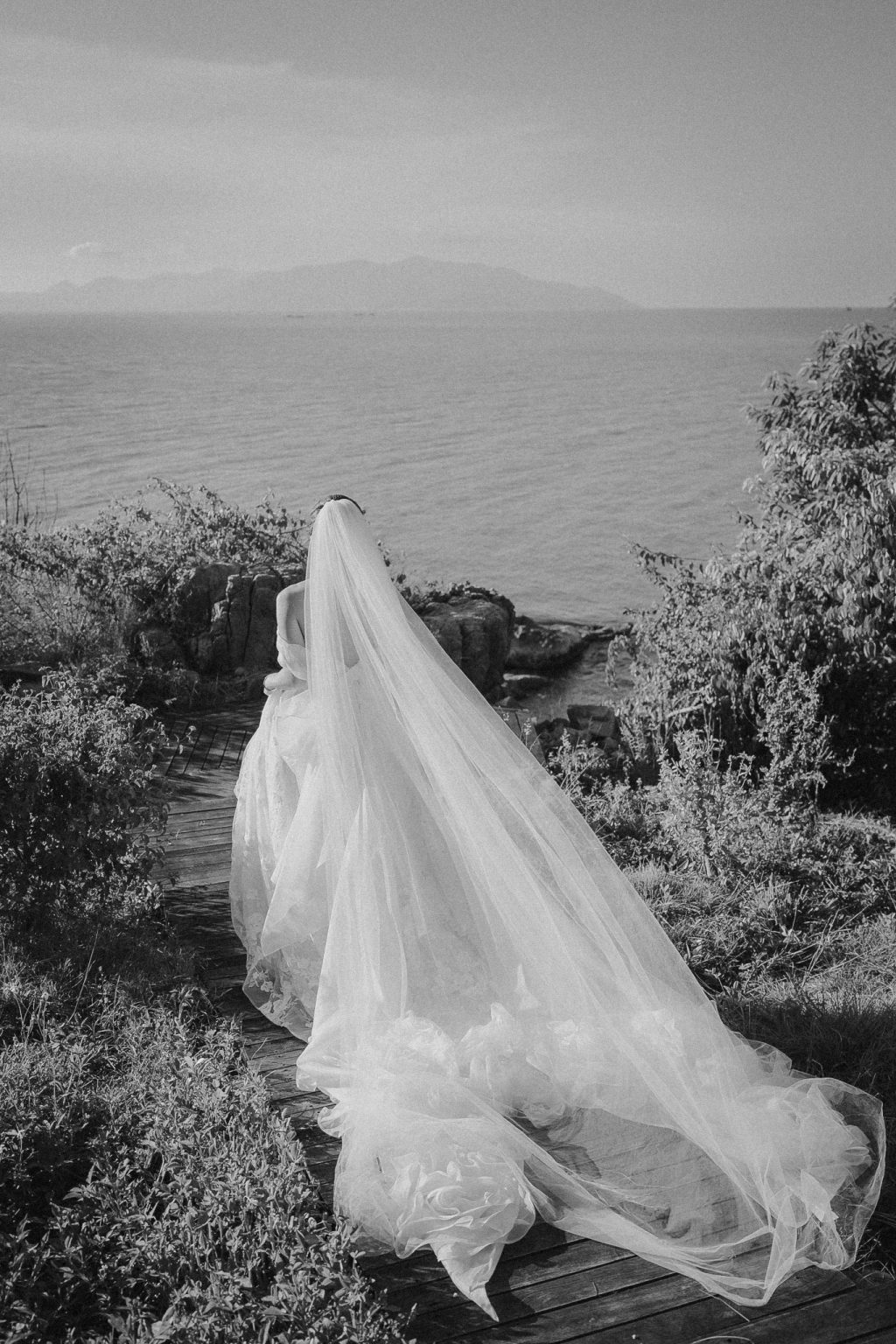 Cbride with long dress walking to oceans cliff