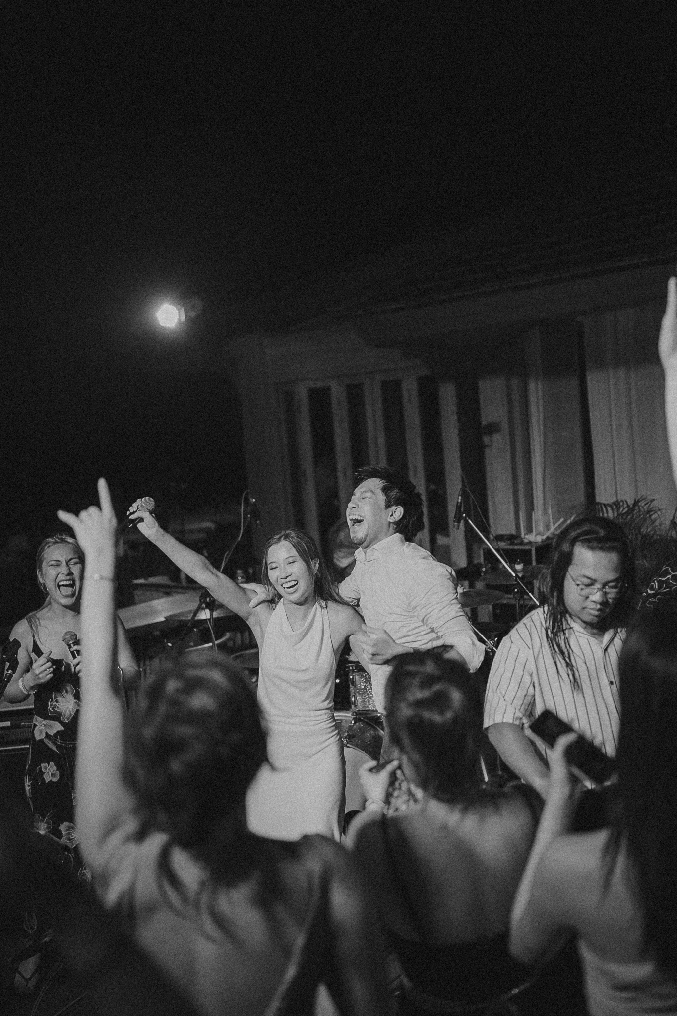 Wedding guests dancing and cheering at a late-night reception, black and white