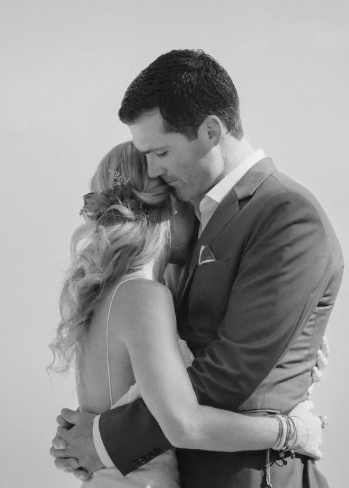 A black-and-white image of a couple embracing closely, conveying love and tenderness.